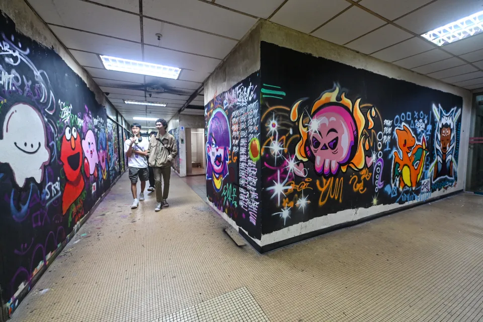 people-walk-past-murals